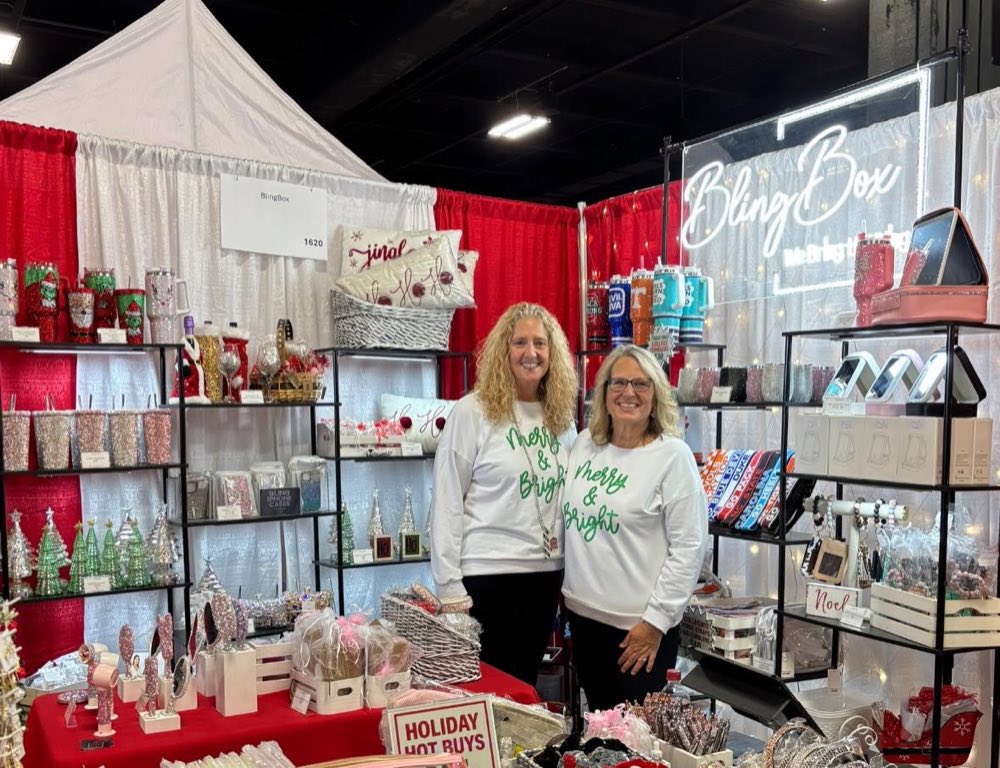 The BlingBox owners at their vendor show booth, surrounded by rhinestone tumblers and holiday gifts